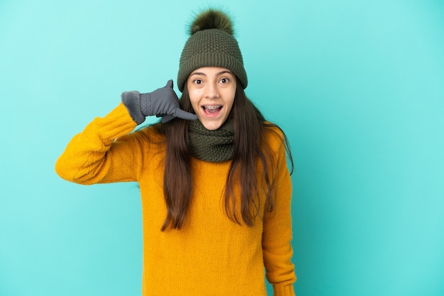 Jong Frans meisje geïsoleerd op blauwe achtergrond met winter hoed telefoon gebaar maken. Bel me terug teken