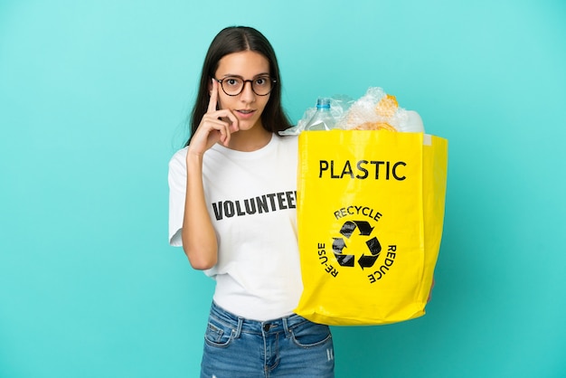 Jong Frans meisje met een zak vol plastic flessen om te recyclen, denkend aan een idee