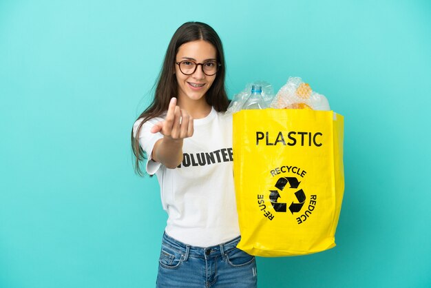 Jong Frans meisje met een zak vol plastic flessen om te recyclen en uitnodigend om met de hand te komen. Blij dat je gekomen bent