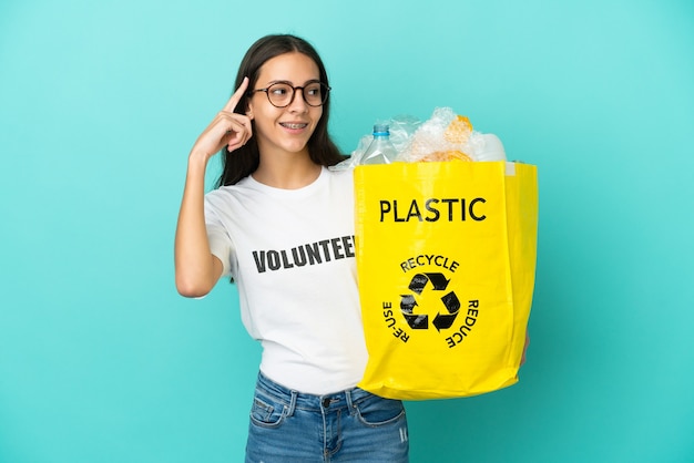 Jong Frans meisje met een zak vol plastic flessen om te recyclen, twijfelt en denkt na