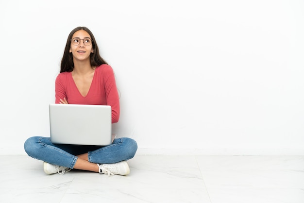 Jong Frans meisje zittend op de vloer met haar laptop opzoeken terwijl lachend