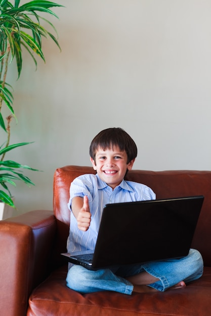 Jong geitje dat zijn laptop met omhoog duim gebruikt