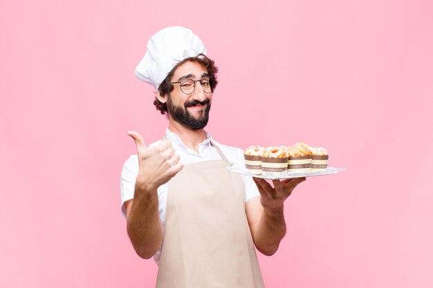 Jong gek banketbakkerijconcept van de bakkersmens tegen roze muur