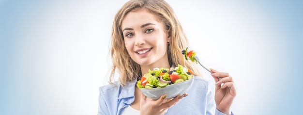 Jong gelukkig blondemeisje die gezonde salade eten.