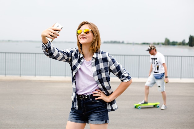 Jong gelukkig meisje in hipster selfie maken op telefoon.