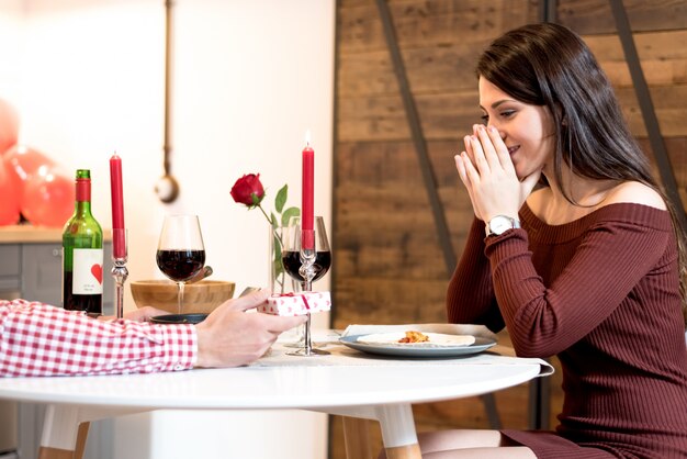 Jong gelukkig paar dat de dag van Valentine met een diner viert dat thuis wijn, toejuicht drinkt.