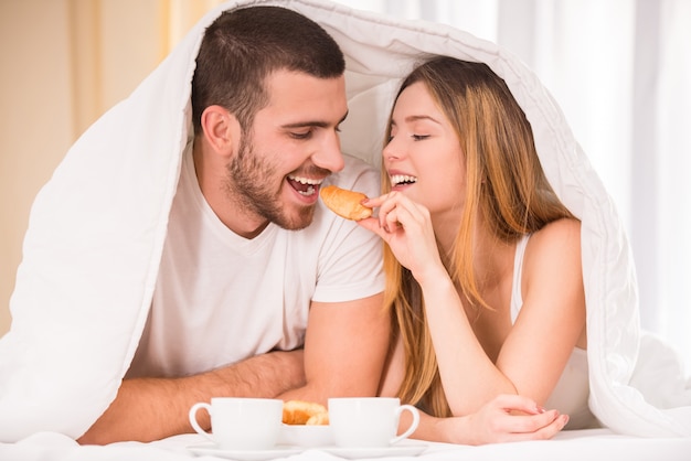 Jong gelukkig paar dat ontbijt in haar slaapkamer eet.