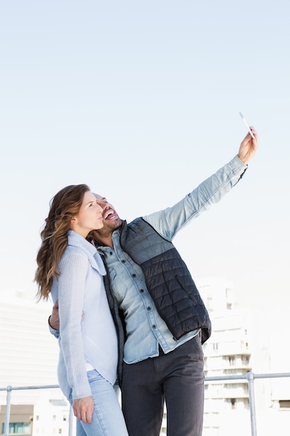 Jong gelukkig paar die selfie op mobiele telefoon in openlucht nemen