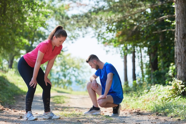 Foto jong gelukkig stel geniet van een gezonde levensstijl tijdens het joggen op een landweg door het prachtige zonnige bos, lichaamsbeweging en fitnessconcept