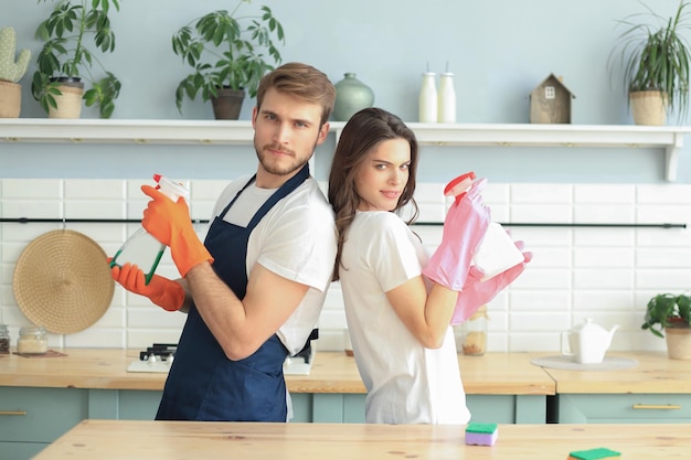 Jong gelukkig stel heeft plezier tijdens het schoonmaken thuis.