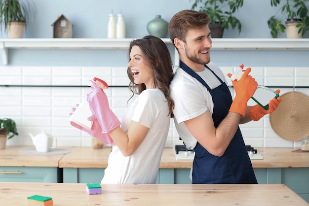 Jong gelukkig stel heeft plezier tijdens het schoonmaken thuis.