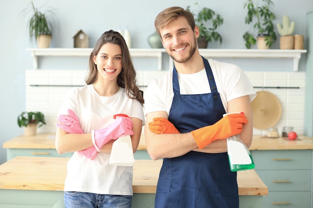 Jong gelukkig stel heeft plezier tijdens het schoonmaken thuis.