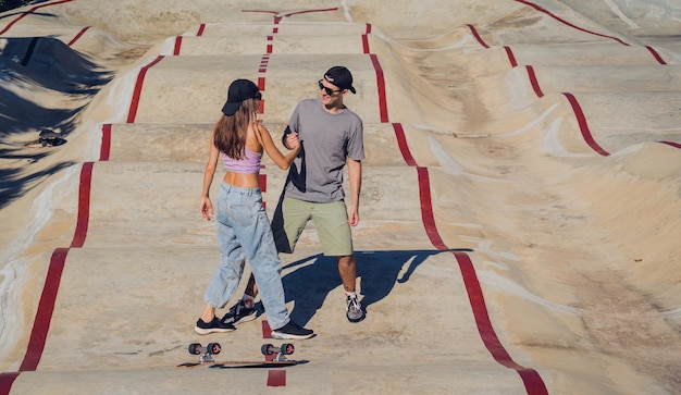 Jong gelukkig stel met skateboards geniet van longboarden in het skatepark