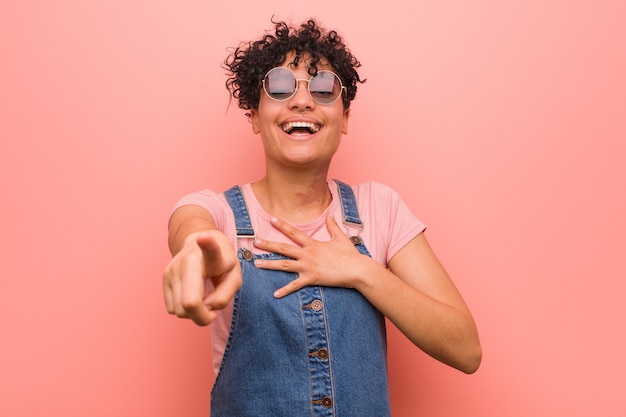 Jong gemengd Afro-Amerikaanse tiener vrouw punten met duim vinger weg, lachen en zorgeloos.