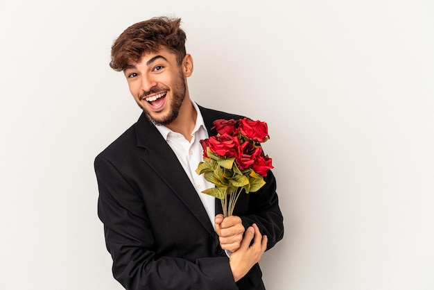 Jong gemengd ras man met boeket rozen geïsoleerd op een witte achtergrond lachen en plezier hebben.
