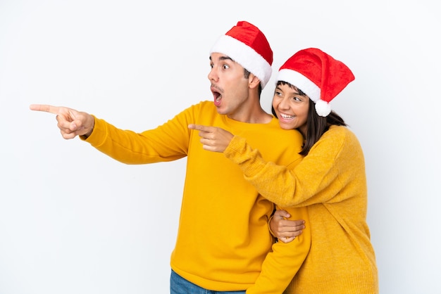 Jong gemengd raspaar dat Kerstmis viert dat op witte achtergrond wordt geïsoleerd en een idee voorstelt terwijl het glimlachen naar