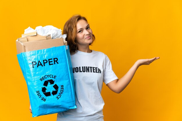 Jong Georgisch meisje dat een recyclingzak vol papier vasthoudt om haar handen opzij te strekken om uit te nodigen om te komen