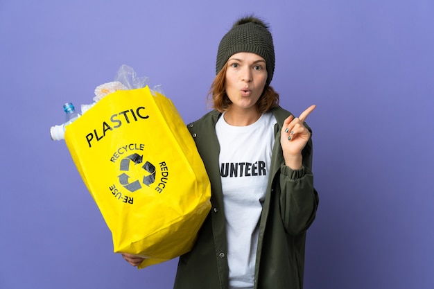 Jong Georgisch meisje dat een zak vol plastic flessen houdt om te recyclen