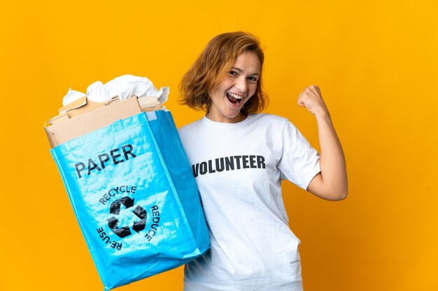 Jong Georgisch meisje met een recyclingzak vol papier om te recyclen terwijl ze een overwinning viert