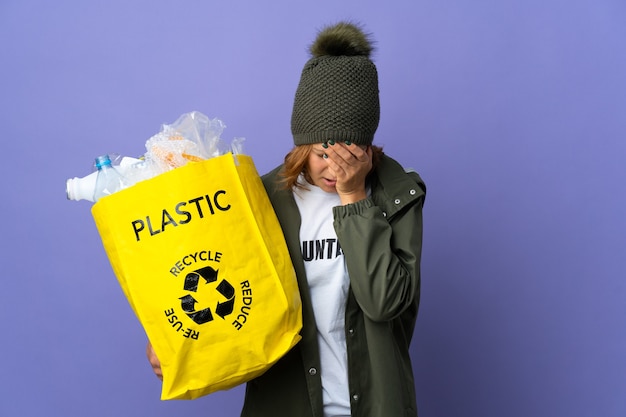 Jong georgisch meisje met een zak vol plastic flessen om te recyclen met een vermoeide en zieke uitdrukking