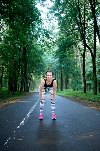 Jong geschikt meisje dat sportkleding draagt die bereid wordt te lopen en aan muziek luistert. Gezonde sportlevensstijl. Fitness en training buiten.