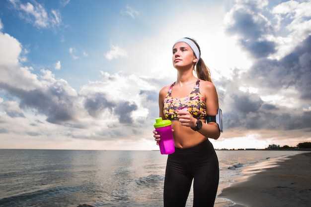 Jong geschikt meisje die op strand bij zonsopgang lopen