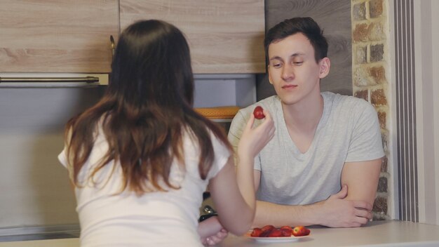 Jong getrouwd stel aan een tafel met wijn en aardbeien. romantische avond.