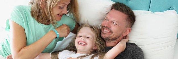 Foto jong getrouwd stel en kind liggend in bed in hotelkamer