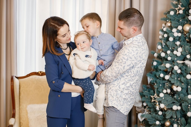 Jong gezin dat thuis in de buurt van de kerstboom staat