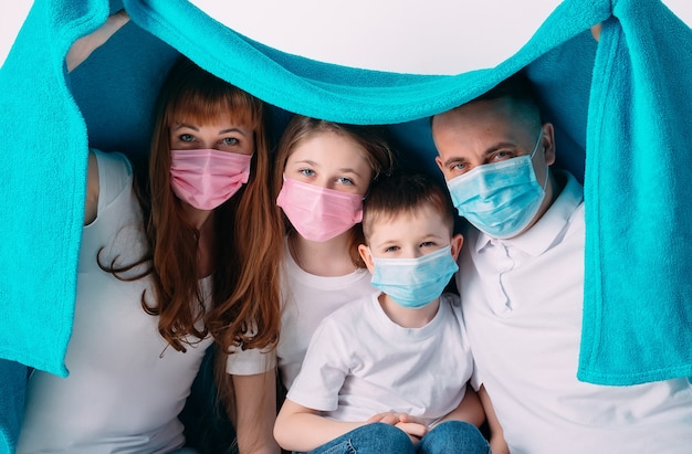 Jong gezin in medische maskers tijdens quarantaine thuis.