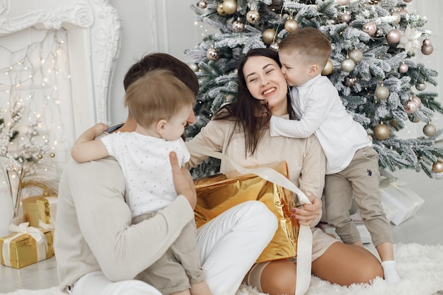 Jong gezin in witte kleren bij de kerstboom