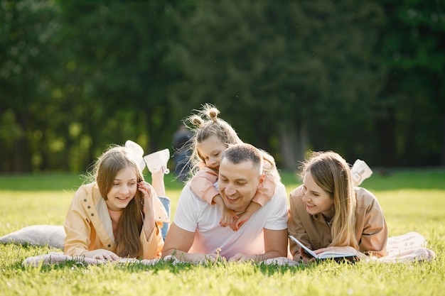 Jong gezin liggend op een gras in een park en een boek lezen