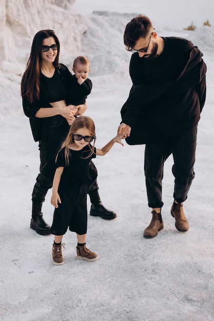 Jong gezin met 2 kinderen gekleed in zwarte kleding poseren voor een foto tijdens een gestileerde fotoshoot op een natuurlijk witte locatie leuk stijlvol en charismatisch Gezin met twee dochters