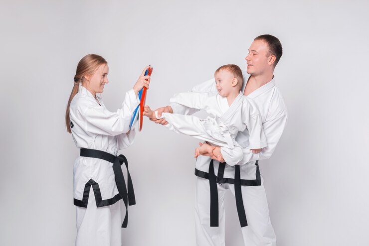 Jong gezin met hun kleine jongen die vechtsporten op wit beoefent