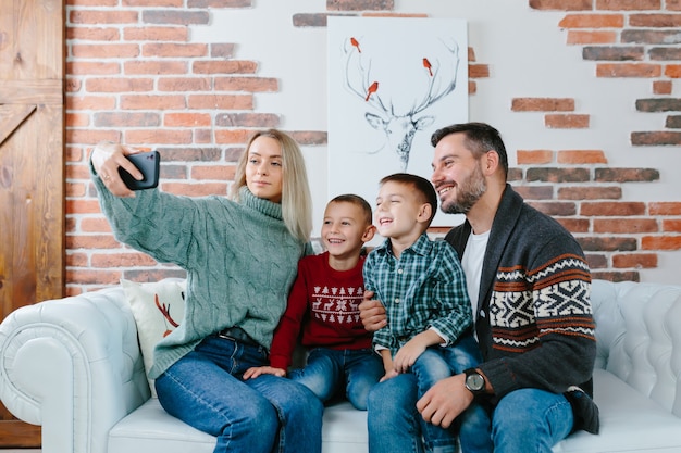 Jong gezin met plezier praten op een video-oproep met behulp van een mobiele telefoon, vreugde en glimlachen, man, vrouw en je jongens broers begroeten vrienden met nieuwjaar en kerstvakantie