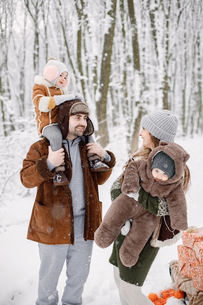 Jong gezin met twee kinderen die in het winterbos staan en poseren voor een foto