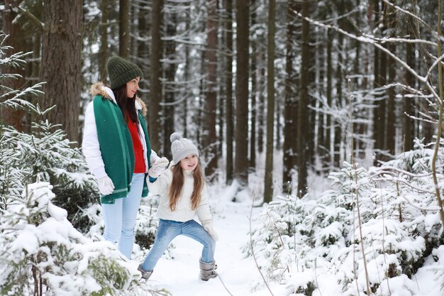 Jong gezin voor een wandeling. Moeder en dochter lopen in een winterpark.