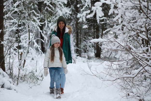 Jong gezin voor een wandeling. Moeder en dochter lopen in een winterpark.