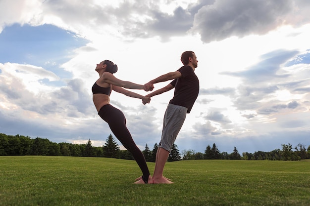 Foto jong gezond koppel doet acro yoga in het zonnige zomerpark fitness en gezonde levensstijl