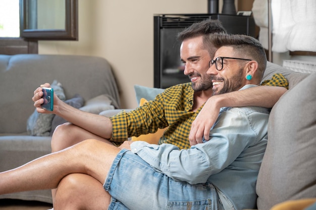 Jong glimlachend homopaar dat thuis selfie neemt