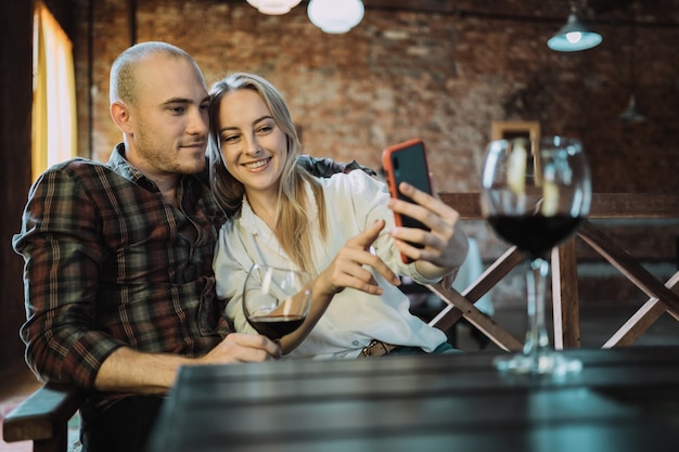 Jong, glimlachend paar zittend aan de tafel van een restaurant en het nemen van een selfie.