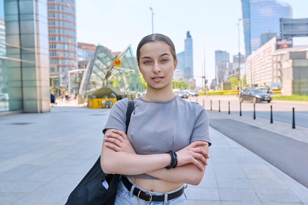 Foto jong glimlachend tienermeisje kijkt naar de camera op straat van een moderne stad