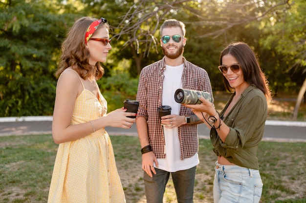 Jong hipster-gezelschap van vrienden die samen plezier hebben in het park, glimlachend luisterend naar muziek op het zomerseizoen van de draadloze luidspreker