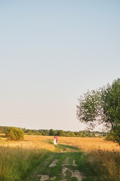 Foto jong huwelijkspaar die op gebied lopen. donkere bewolkte dag van de retro stijl de pluizige kleding