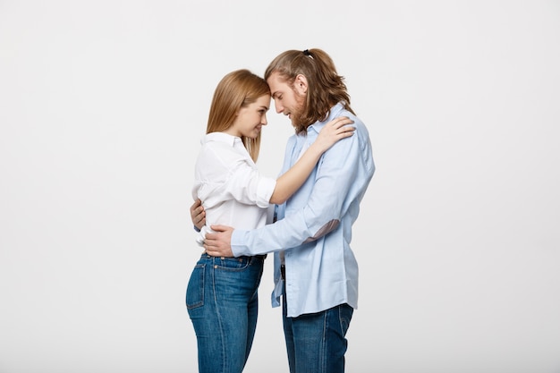 Jong in liefde paar wat betreft voorhoofden en huging over geïsoleerd op een witte achtergrond