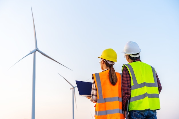 Jong ingenieursteam dat met laptop computer tegen windturbineboerderij werkt