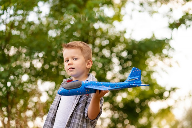 Jong jongensspel met stuk speelgoed airplaine in handen. Happy Kid speelt buiten in het park.