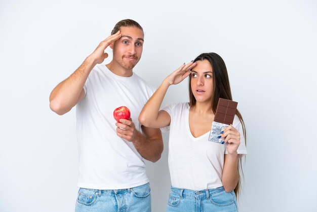 Jong Kaukasisch koppel met chocola en appel geïsoleerd op een witte achtergrond heeft net iets gerealiseerd en heeft de oplossing voor ogen