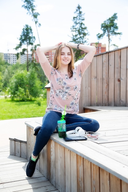 Jong Kaukasisch meisje geniet van de zon zittend op een houten podium