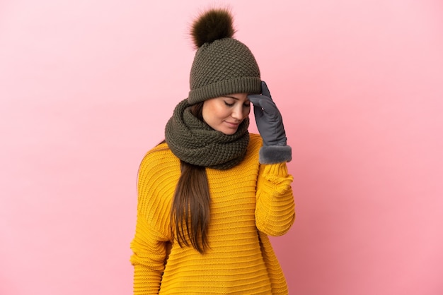 Jong Kaukasisch meisje met wintermuts geïsoleerd op roze achtergrond lachen